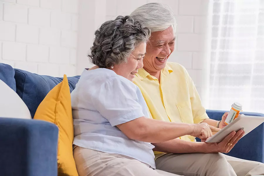 medicare part d plan couple use a tablet to video conference with their doctor about prescription while sitting on sofa at home